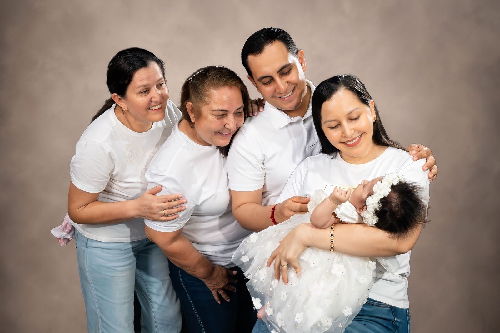 Tres generaciones de una familia sonriendo alrededor de una bebé recién nacida