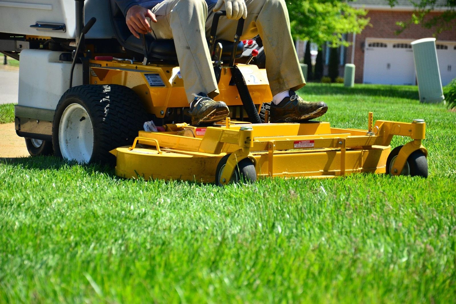 A landscaper cutting a lawn with a riding mower