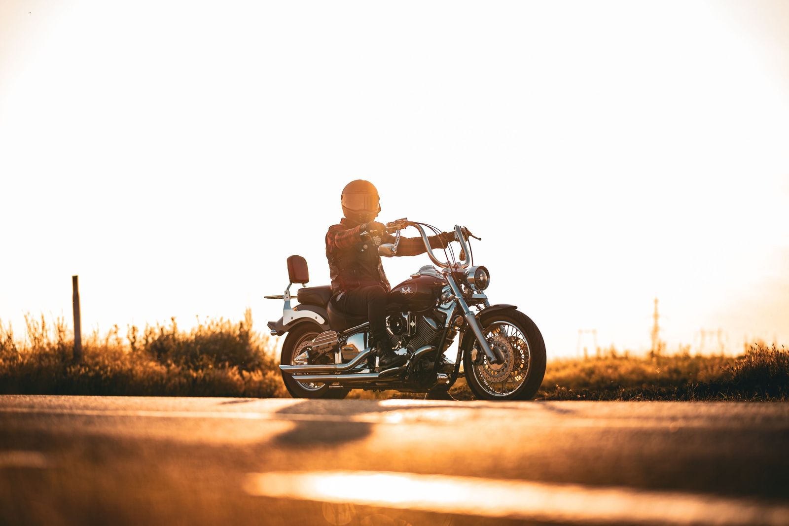 Un motociclista en una moto cruiser en la carretera al atardecer
