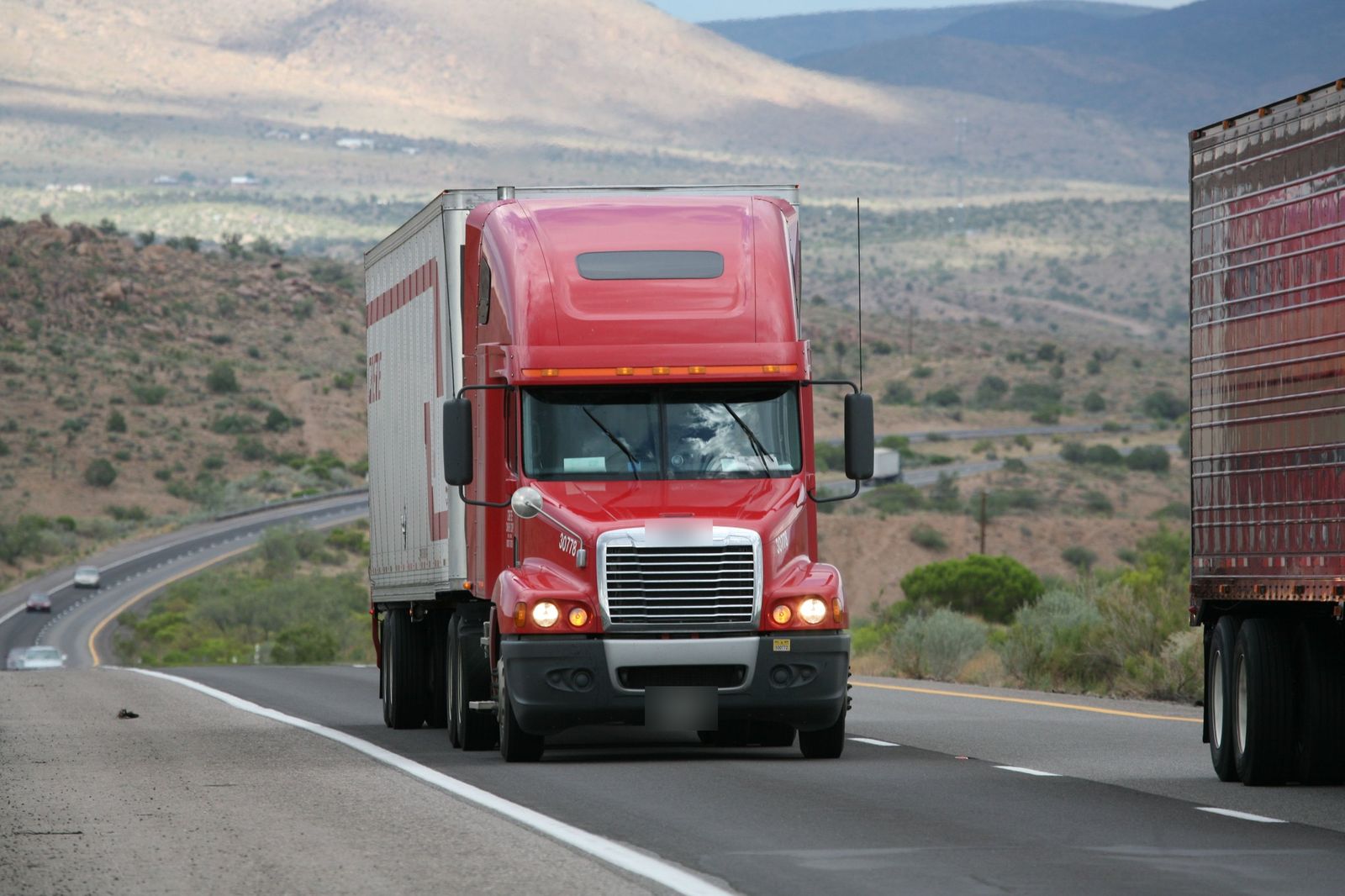 Un tráiler rojo en una carretera entre montañas