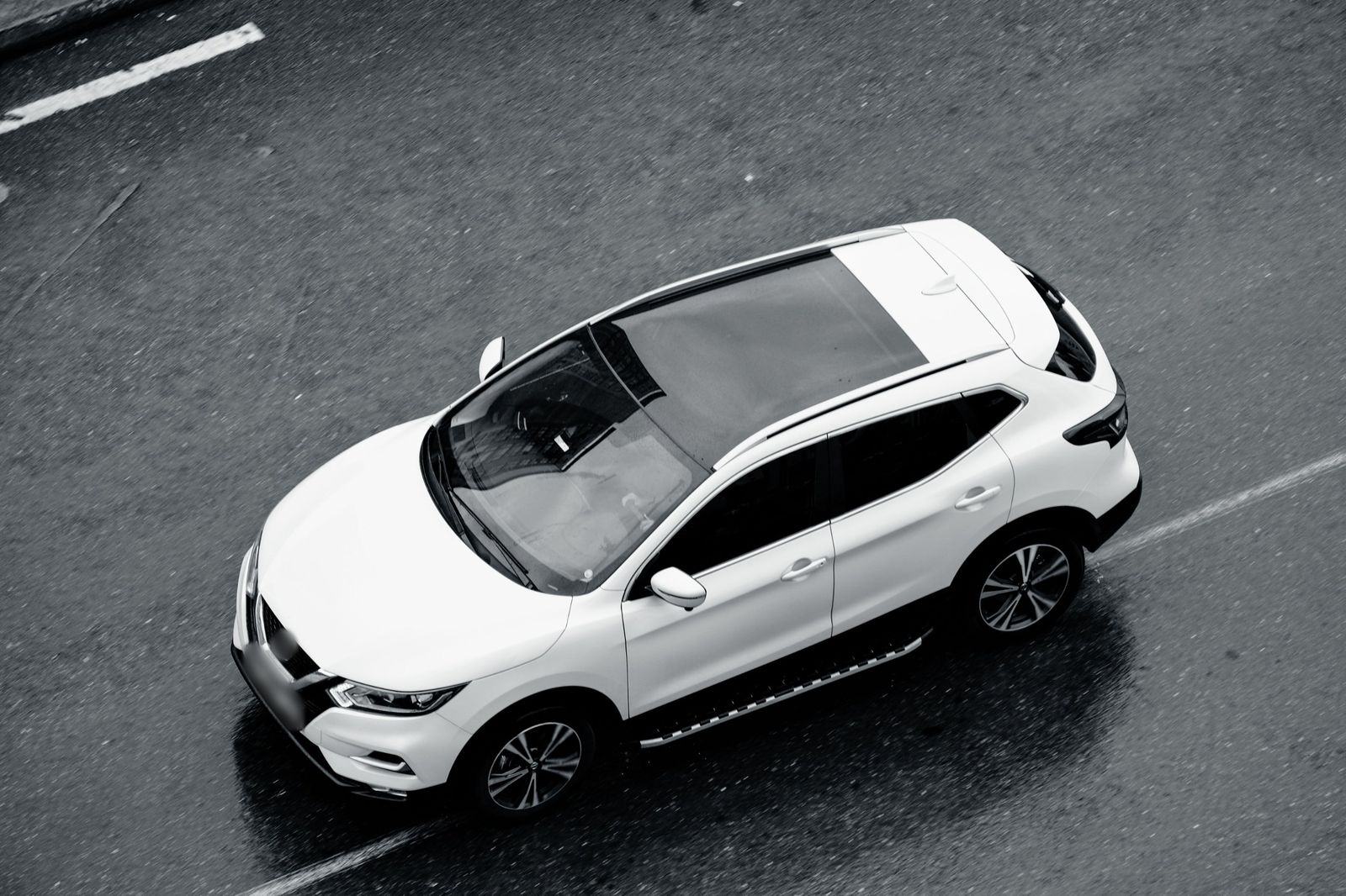 A white SUV driving on a wet road